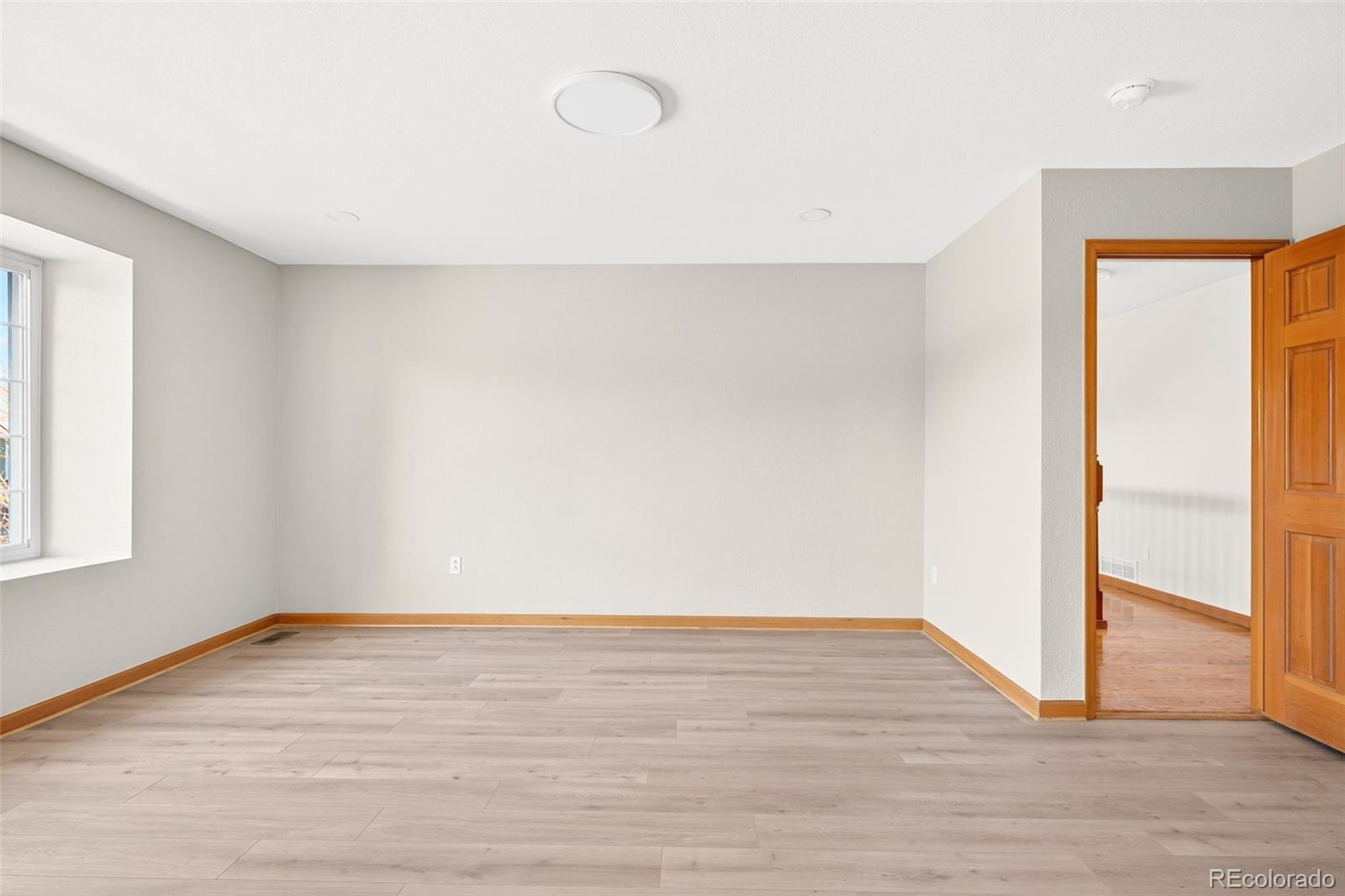 8852 Chestnut Hill Lane Highlands Ranch, CO 80130 - Photo 18 of 38 a view of an empty room with wooden floor and a window