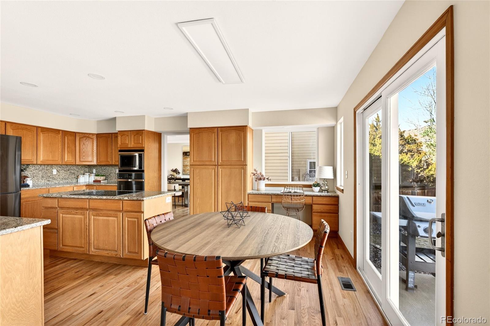 8852 Chestnut Hill Lane Highlands Ranch, CO 80130 - Photo 7 of 38 a kitchen with a table chairs refrigerator and cabinets