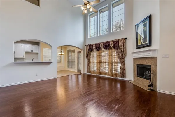 a view of an empty room with wooden floor and a fireplace