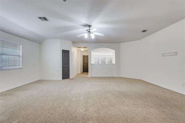 an empty room with chandelier fan and windows