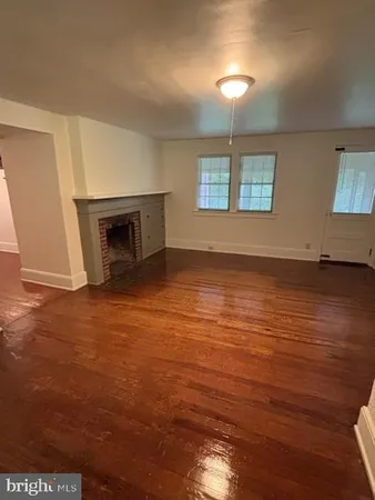 an empty room with wooden floor fireplace and windows
