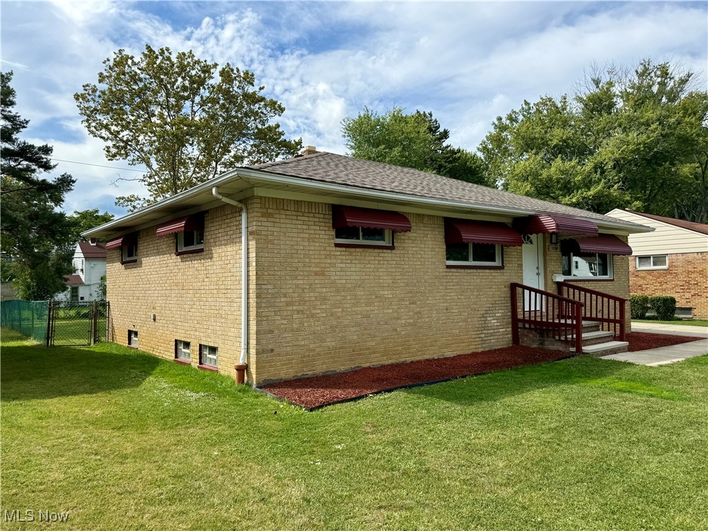 19504 Sumpter Road Cleveland, OH 44128 - Photo 2 of 39 View of side of property featuring brick siding, a yard, and a shingled roof