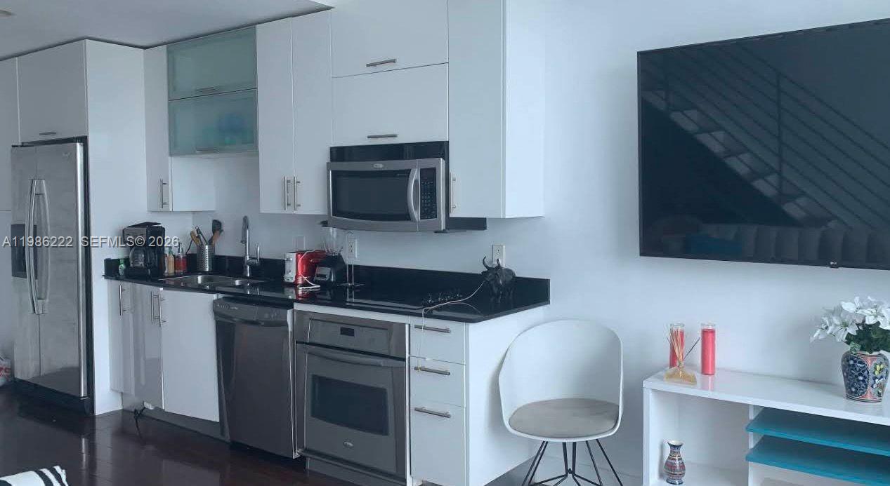 60 Southwest 13th Street, Unit 3017 Miami, FL 33130 - Photo 21 of 46 a kitchen with stainless steel appliances granite countertop a stove a sink and a microwave