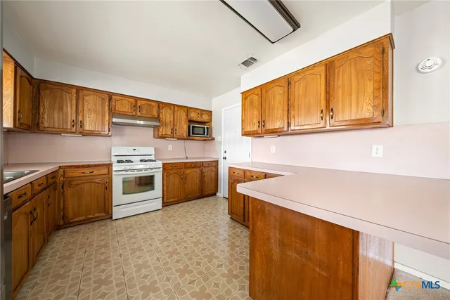 a kitchen with stainless steel appliances granite countertop a stove a sink and a microwave
