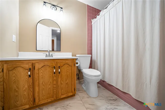 a bathroom with a toilet a sink and curtain