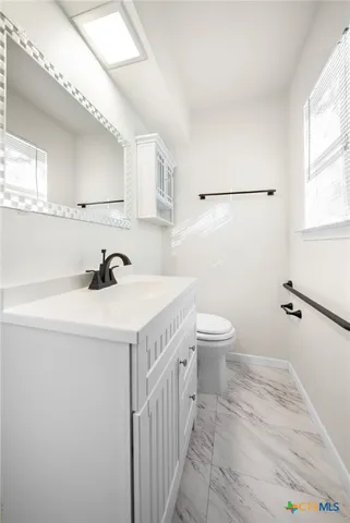 a bathroom with a sink a toilet and a window