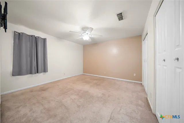 an empty room with windows and fan