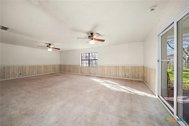 an empty room with windows and fan