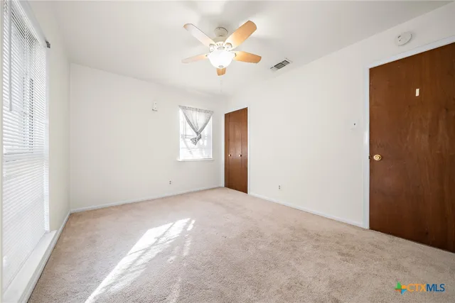 an empty room with closet and fan