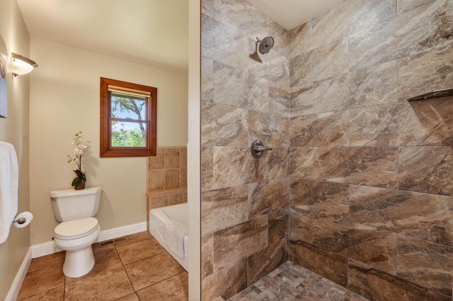 7021 Horseshoe Bar Road Loomis, CA 95650 - Photo 28 of 77 Tiled walk-in shower featuring a built-in shelf and mosaic floor
