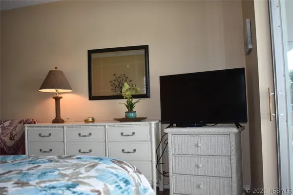 a bedroom with a bed and a flat tv screen on dresser