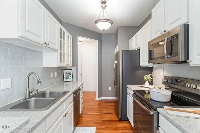 a kitchen with stainless steel appliances granite countertop a sink stove refrigerator and cabinets