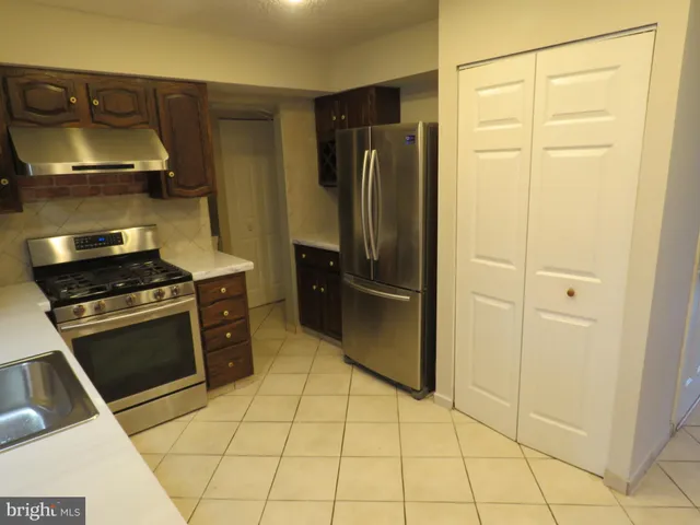a kitchen with granite countertop a refrigerator and a stove top oven