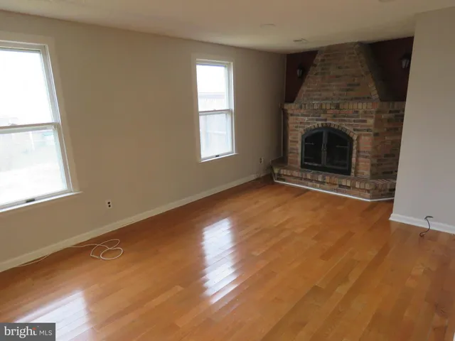 an empty room with windows and fireplace