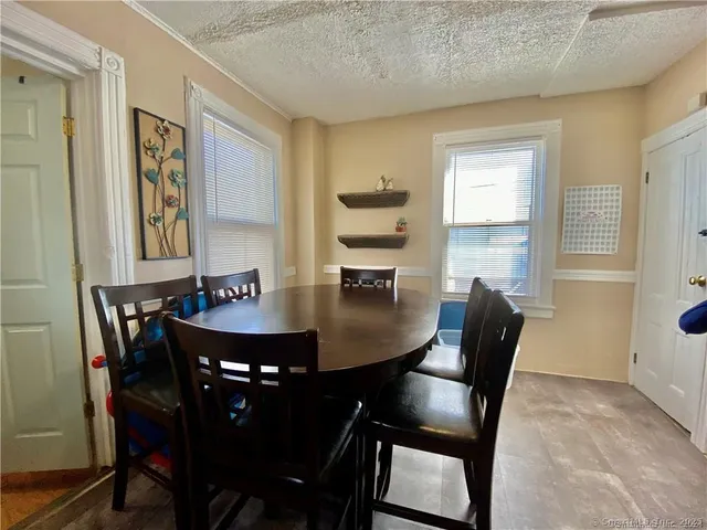 a kitchen with stainless steel appliances granite countertop a stove a refrigerator a dining table and chairs with wooden floor