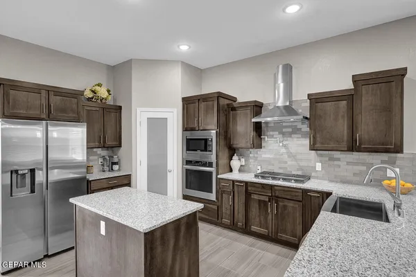 a kitchen with stainless steel appliances kitchen island granite countertop a refrigerator and a stove
