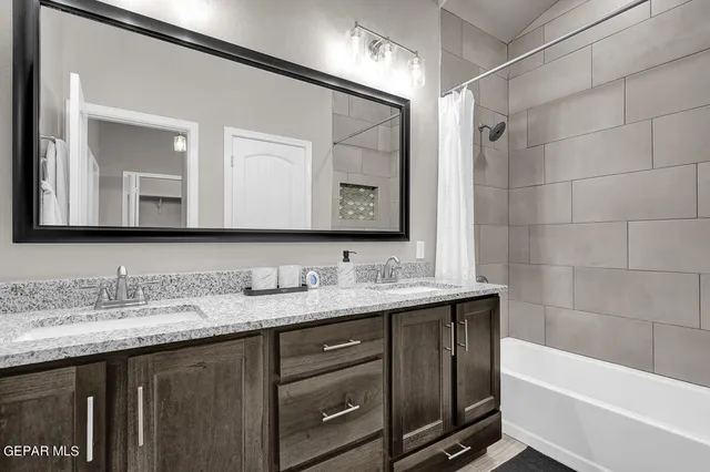 a bathroom with a granite countertop sink mirror and a bathtub