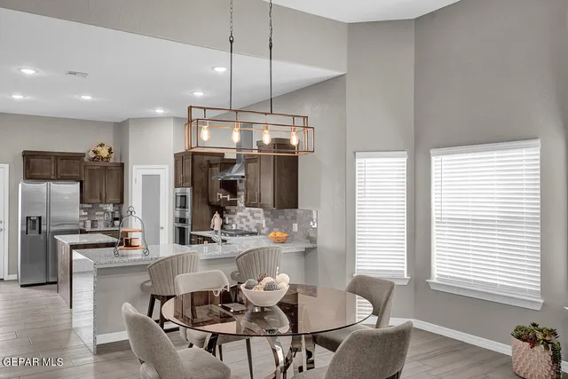 a dining room with stainless steel appliances kitchen island granite countertop a table chairs and a refrigerator