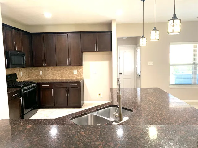 a kitchen with stainless steel appliances granite countertop a refrigerator a stove and a sink with wooden cabinets