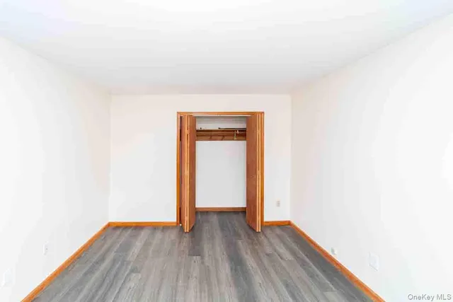 a view of an empty room with wooden floor and closet