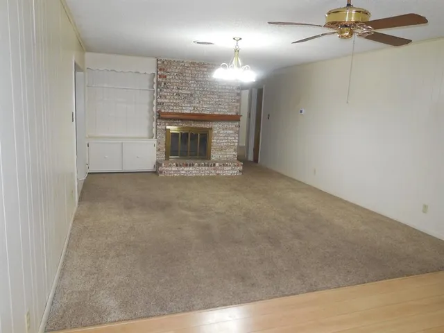 an empty room with windows and fireplace