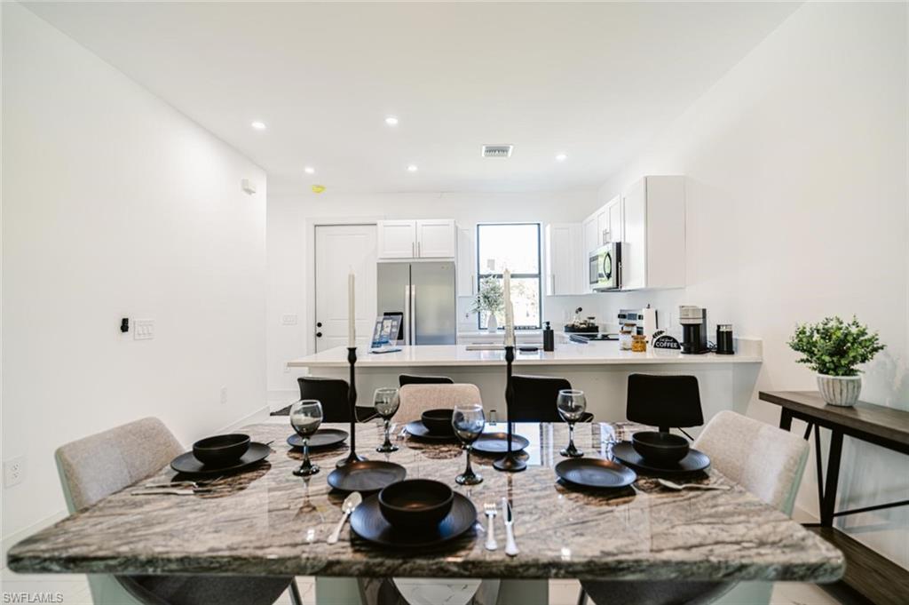 907 Homestead Road South Lehigh Acres, FL 33974 - Photo 11 of 43 Spacious dining area with a polished stone-finish table, recessed lighting, and bright white walls