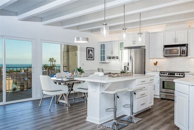 a kitchen with stainless steel appliances a dining table chairs stove refrigerator and cabinets