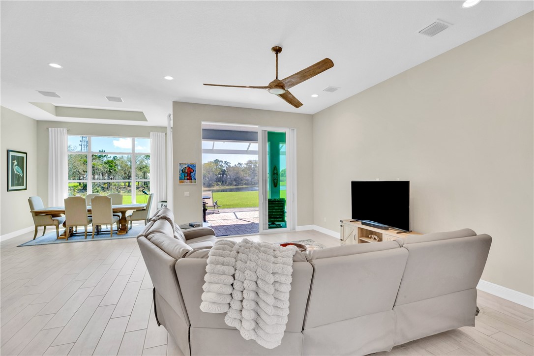 105 Night Hawk Way Sebastian, FL 32958 - Photo 13 of 36 a living room with furniture a flat screen tv and a floor to ceiling window