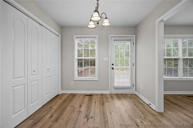 an empty room with wooden floor cabinet and windows