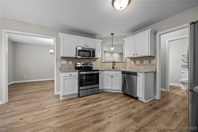 a kitchen with stainless steel appliances a sink cabinets and wooden floor