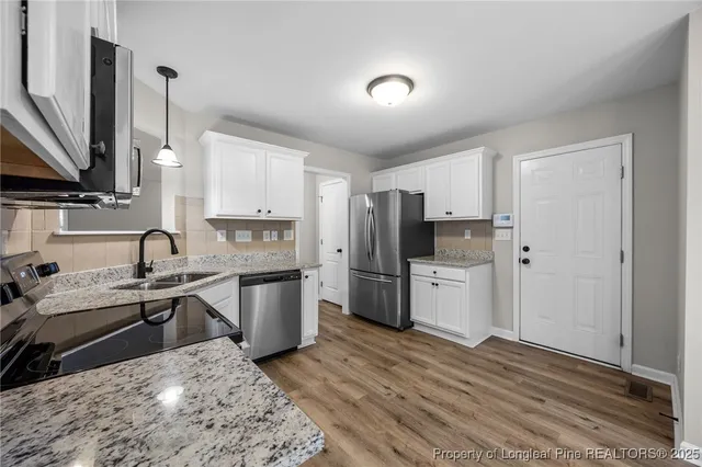 a kitchen with stainless steel appliances granite countertop a sink stove and refrigerator