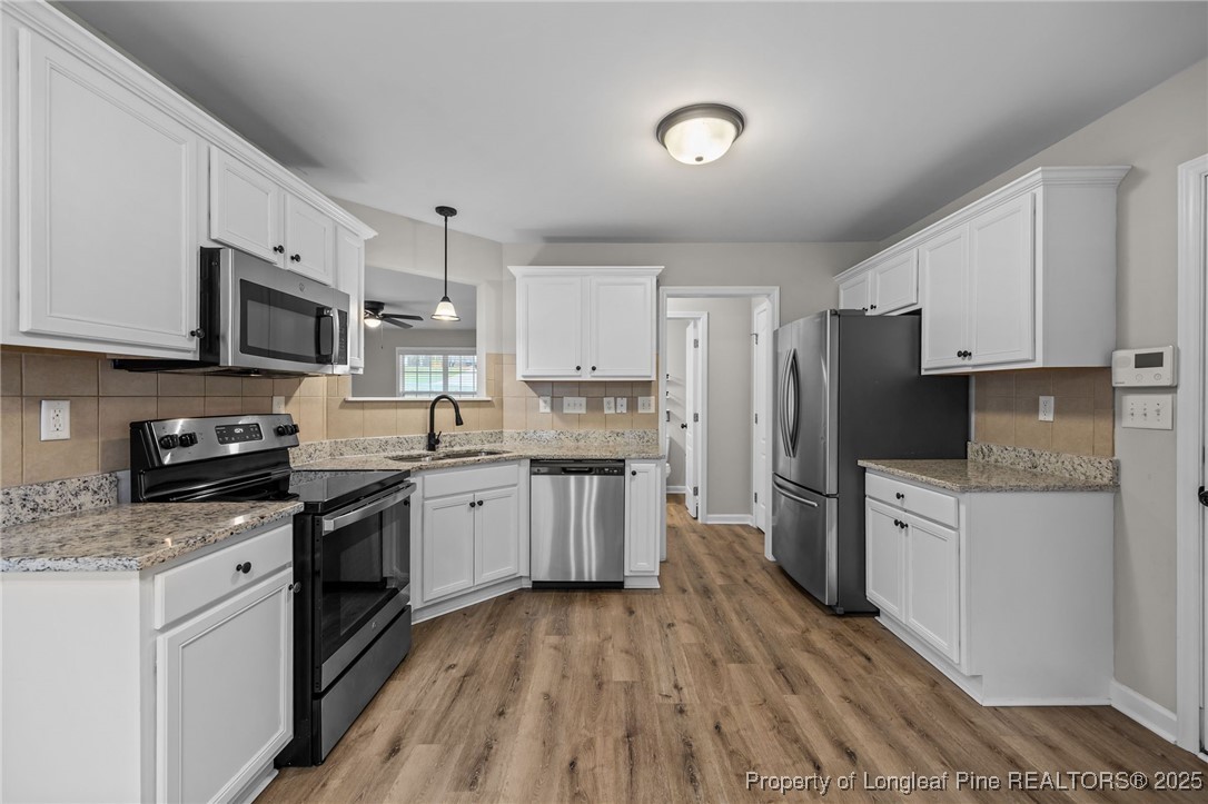 216 Cobblestone Drive Spring Lake, NC 28390 - Photo 33 of 38 a kitchen with granite countertop a stove top oven a sink dishwasher a refrigerator and white cabinets with wooden floor
