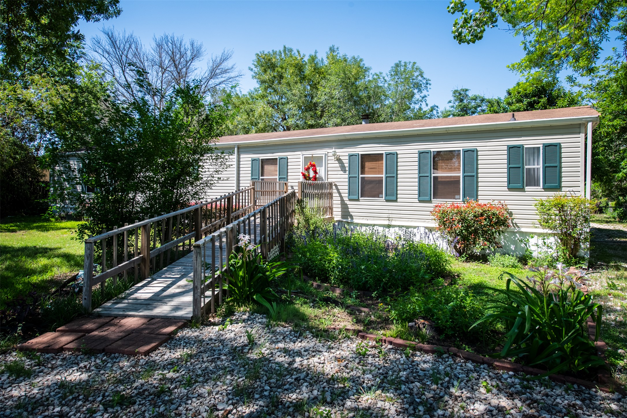 258 Quail Ridge Drive Kyle, TX 78640 - Photo 6 of 11 Exterior featuring light-colored siding, dark green shutters, and a wooden ramp leading to the front entry