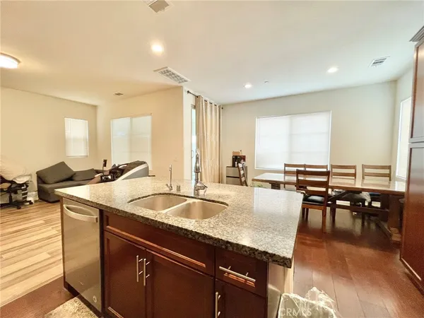 a dining hall with stainless steel appliances granite countertop a sink a table and chairs