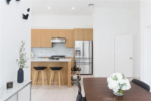 a kitchen with stainless steel appliances granite countertop a stove a refrigerator a sink a dining table and chairs with wooden floor