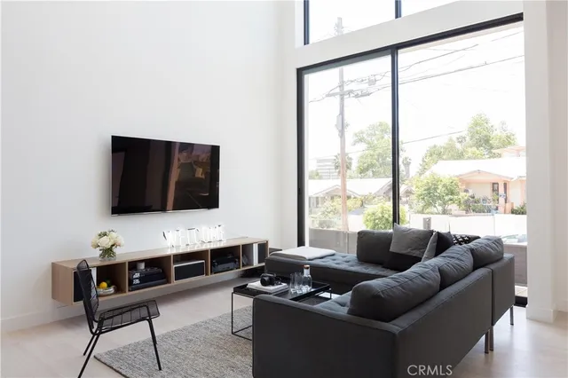 a living room with furniture a flat screen tv and a floor to ceiling window