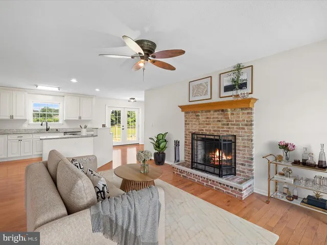 a view of an empty room with wooden floor fireplace and a window