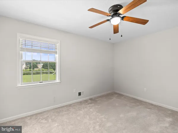 an empty room with a window and a fan