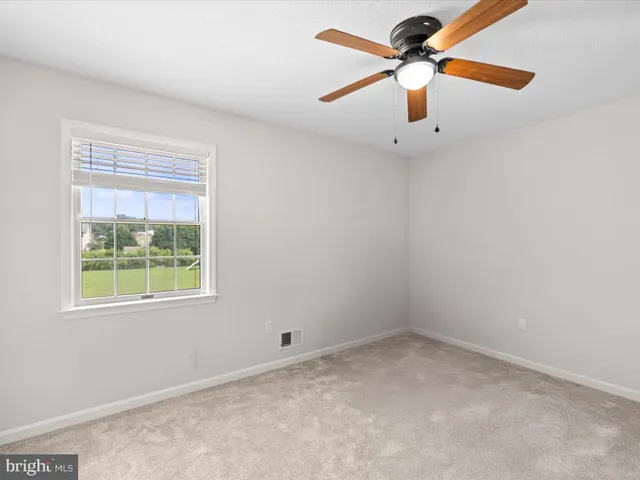 an empty room with a window and a fan