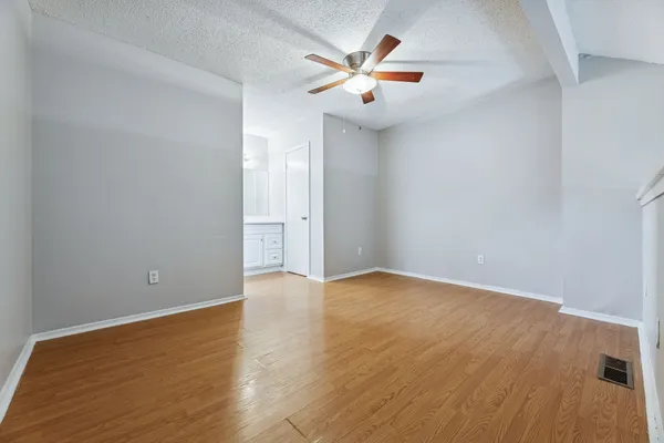 an empty room with wooden floor and windows