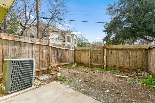 a backyard of a house with a large tree and wooden fence