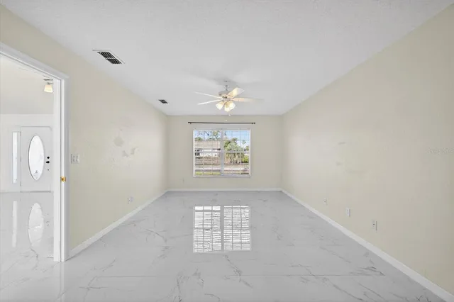 an empty room with windows and fan