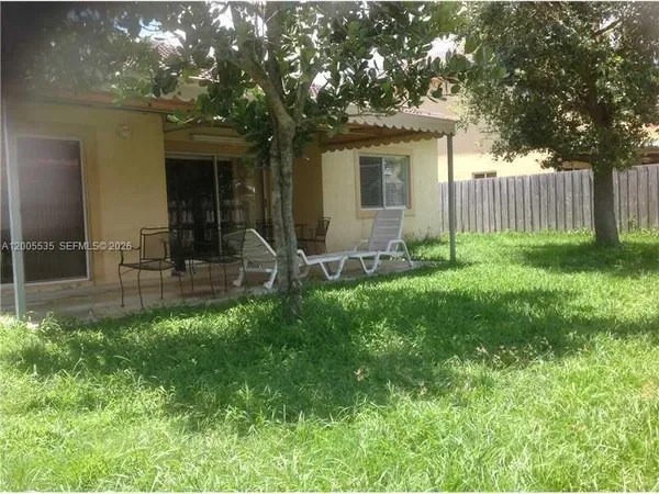 a view of backyard with table and chairs and wooden fence