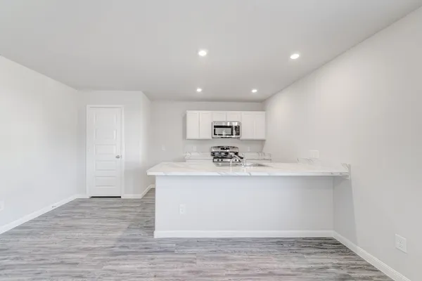 a view of kitchen with stainless steel appliances granite countertop a sink and a refrigerator