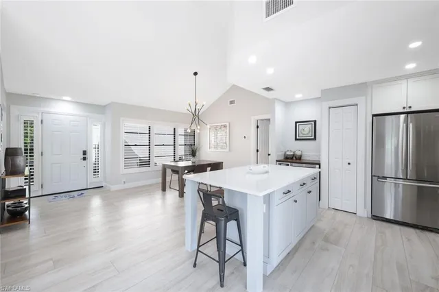 a kitchen with stainless steel appliances a refrigerator a sink dishwasher a stove and white cabinets with wooden floor