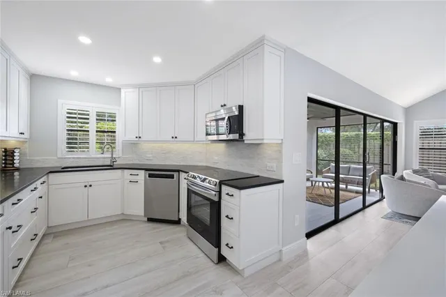 a kitchen with granite countertop cabinets stainless steel appliances and a large window
