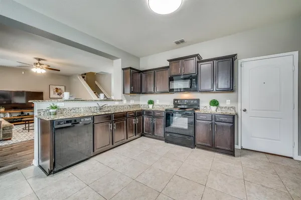 a kitchen with stainless steel appliances granite countertop a stove top oven a sink and a refrigerator