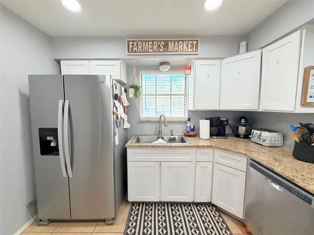a kitchen with granite countertop a stove a sink and a refrigerator