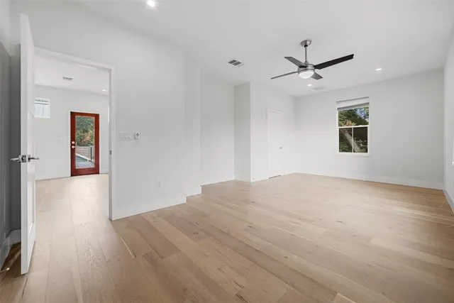 a view of empty room with wooden floor and fan