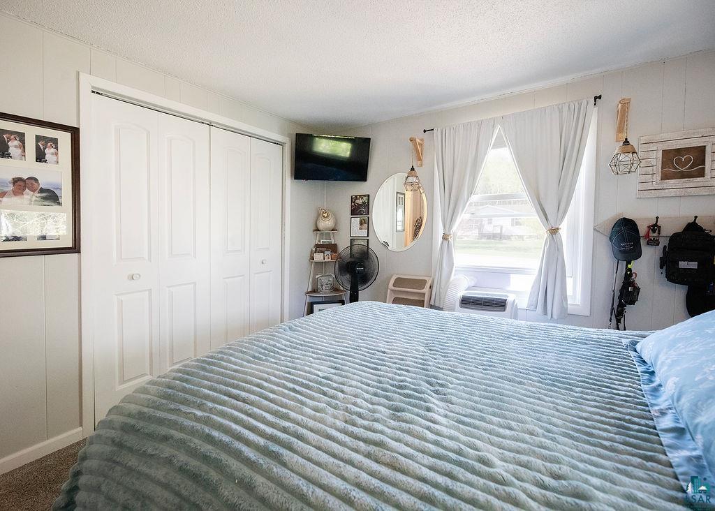 216 13th Street Proctor, MN 55810 - Photo 15 of 18 Room featuring board and batten walls, neutral carpeting, a double window, and white bi-fold closet doors